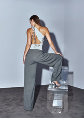 Woman in a white top and gray pants posing on a clear platform against a plain background